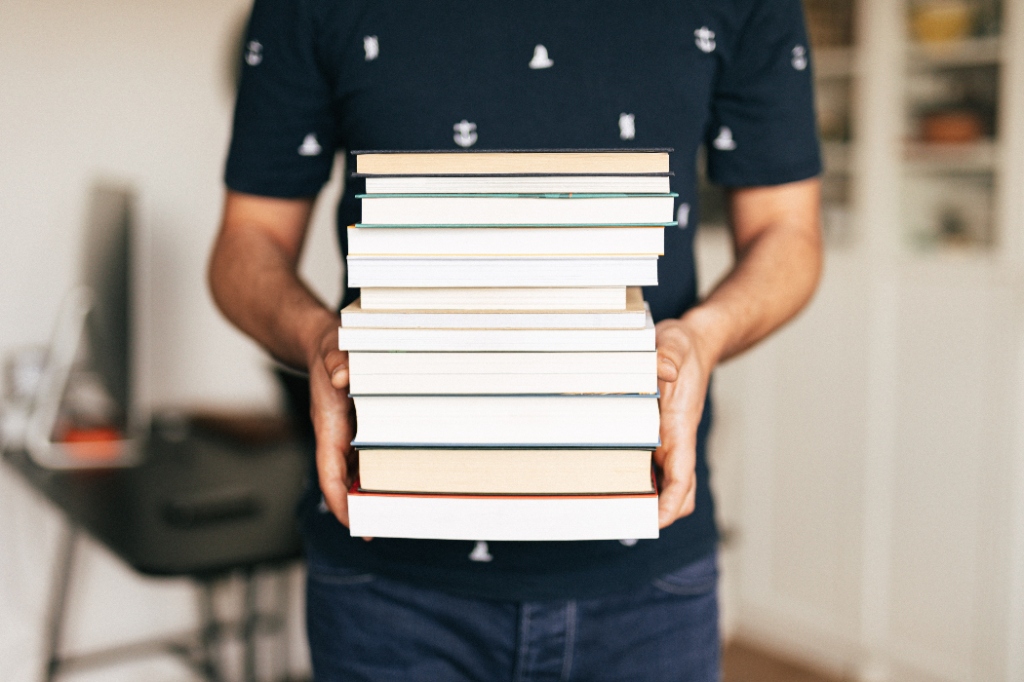 A person carrying a stack of books